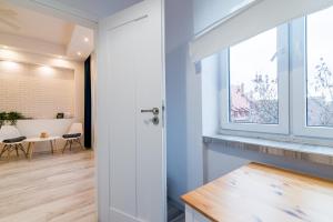 Zimmer mit weißen Wänden, einem Fenster und einem Tisch in der Unterkunft Lux Apartment in white in Danzig