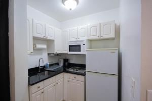 a kitchen with white cabinets and a white refrigerator at Studio Plus - One-Bedroom APT in New York