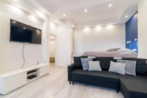 ein Wohnzimmer mit einem Sofa und einem TV an der Wand in der Unterkunft Lux Apartment in white in Danzig