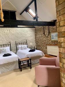a bedroom with two beds and a couch and a brick wall at The Old Stable in Sleaford