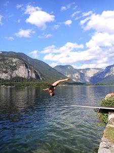 a man is doing a jump into a lake at Apartments Marie B in Hallstatt