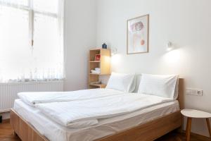 1 dormitorio con 1 cama grande con sábanas blancas en Check-in Apartments, en Leópolis