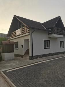 uma casa branca com um telhado preto e uma entrada em Casa Madalina em Săpînţa