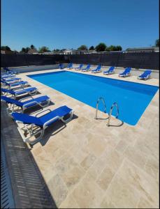 - une piscine bordée de chaises longues bleues dans l'établissement Camping le Clos Savoye, à Biville-sur-Mer