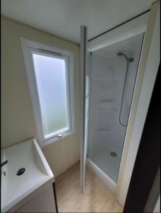 La salle de bains est pourvue d'une douche, d'un lavabo et d'une fenêtre. dans l'établissement Camping le Clos Savoye, à Biville-sur-Mer
