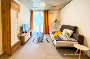 a living room with a couch and a television at Boarding Apartments Kolbermoor in Kolbermoor