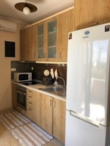 a kitchen with wooden cabinets and a white refrigerator at AM Beach House in Nea Moudania