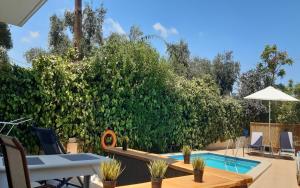 a backyard with a swimming pool and a hedge at Marianna Apartments in Almyrida