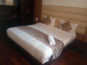 un grande letto con lenzuola e cuscini bianchi di Tavisha Kanatal Hills Chamba a Kanatal