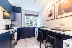 a kitchen with blue cabinets and black stools at Realm choice estates in Catford