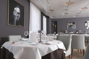 une salle à manger avec une table et des nappes blanches dans l'établissement Boutique Hôtel de l'Ecu Vaudois, à Begnins