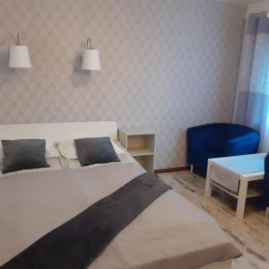 a bedroom with a bed and a blue chair at domek dla 2 osób in Junoszyno