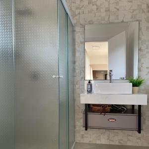 La salle de bains est pourvue d'une douche en verre et d'un lavabo. dans l'établissement Melhor Casa para locação em Pomerode, à Pomerode