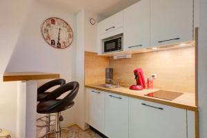 a kitchen with white cabinets and a clock on the wall at Le Brienne Toulouse Centre in Toulouse +10 photos