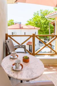 a table with two cups and chairs on a balcony at Harmony House in Platanias