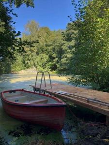 a red boat tied up to a dock at Kleines Ferienhäuschen im Grünen am Wasser in Grönwohld