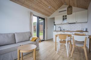 ein Wohnzimmer mit Sofa, Tisch und Stühlen in der Unterkunft SkyView Deluxe Houses and Private Jacuzzi , Osłonino in Osłonino