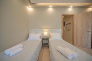 2 camas en una habitación con sábanas y almohadas blancas en El Sueño de Zante 2nd City Center Apartments en Zakynthos