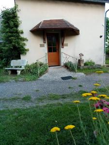 uma casa com uma porta e um banco e flores em Désert et Bocage em Saint-Aubin-le-Monial