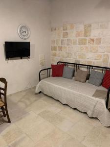 een slaapkamer met een bed en een tv aan de muur bij Casa Uliveto in Alberobello