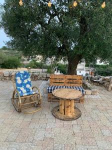 een tafel en een stoel en een tafel en een boom bij Casa Uliveto in Alberobello