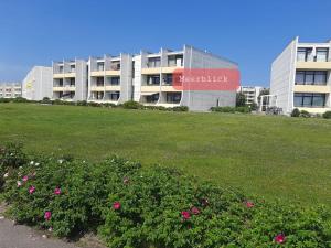 a building with a field of flowers in front of a building at Appartement mit Balkon und Meerblick in Fehmarn