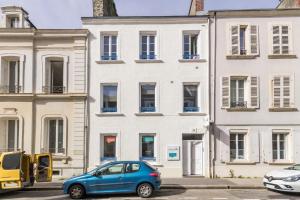 un coche azul estacionado frente a un edificio blanco en LE NID DES MOUETTES en Cherbourg en Cotentin