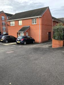a house with two cars parked in a parking lot at Modern stylish flat over garage in Crewe