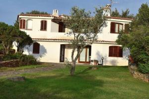 una gran casa blanca con un árbol en el patio en Villa Molara, en Baja Sardinia