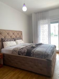 a bedroom with a large bed with a large window at Apartment Vesna City PG in Podgorica