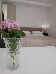 un jarrón con flores rosas en una mesa junto a una cama en Apartmani Dragovic, en Brodarica