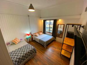 1 dormitorio con 2 camas, lámpara y espejo en VOY Hostales - Poniente, en Viña del Mar