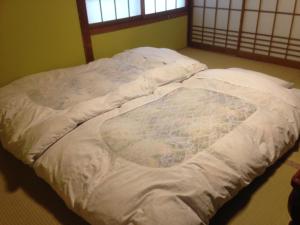 an unmade bed with a blanket on it in a room at Chuokan Shimizuya Ryokan in Nagano