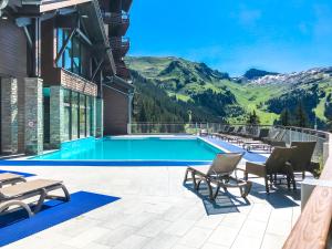 a resort pool with chairs and a view of mountains at Les Terrasses d'Eos, 1-bed apartment with fireplace, Ski in, Ski out in Flaine
