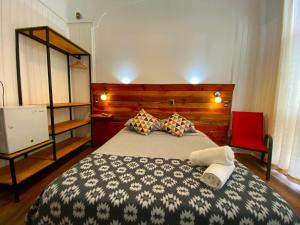 a bedroom with a large bed and a red chair at VOY Hostales - Poniente in Viña del Mar