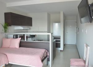 a bedroom with a pink bed and a kitchen at Monoambiente La Pitota in Paraná