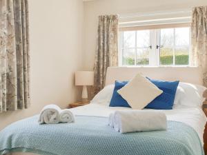 ブリドリントンにあるShepherd's Cottageのベッドルーム1室(青い枕のベッド1台、窓付)