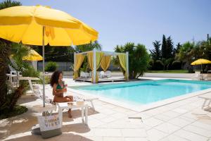 a woman sitting on a chair next to a swimming pool at Dimora Levante in Monteroni di Lecce