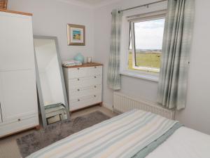 a bedroom with a bed and a window and a dresser at The Nest in Chathill