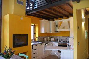 a kitchen with yellow walls and white cabinets at Tramonto Casa Barga Toscana ristrutturata 2021 in Barga