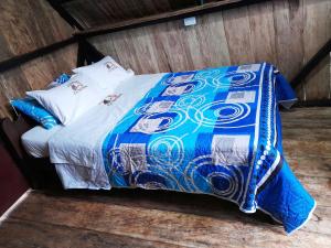 a bed with a blue and white comforter on it at Posada Fin del Mundo in Mocoa