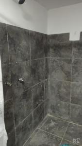 a shower with a black tiled wall in a bathroom at Hostal Da`Silva in Quito
