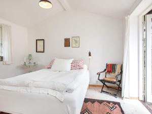ein weißes Schlafzimmer mit einem Bett und einem Stuhl in der Unterkunft Holiday home Fårevejle XII in Fårevejle