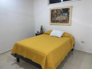 ein Schlafzimmer mit einem Bett mit einer gelben Decke in der Unterkunft Casa Las Palmas in Tizimín