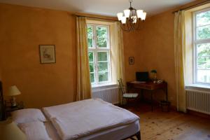 a bedroom with a bed and a desk and windows at Landhaus Schloss Kölzow in Kölzow