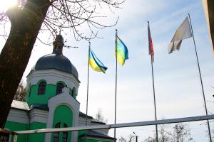 ein grünes Gebäude mit Flaggen auf dem Dach in der Unterkunft Liz - готель, сауна, ресторан in Dunaivtsi