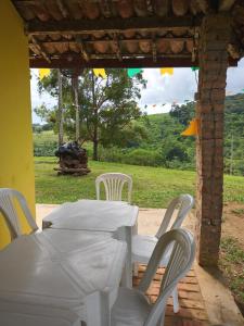 a white table and chairs with a view of a field at Sítio Pé de Serra in Sobradinho