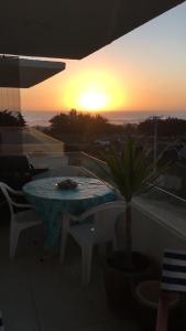 uma mesa e cadeiras numa varanda com o pôr-do-sol em Departamento vista al mar em El Tabo