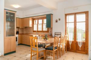 a kitchen with a wooden table and chairs and a table at Villas Alexandros in Kalamaki