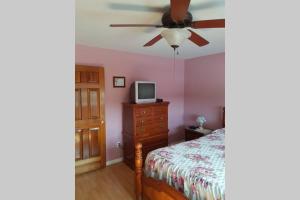 een slaapkamer met een bed en een plafondventilator bij Ocean Front House in Cook's Harbour Newfoundland in Raleigh